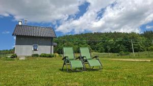 two green chairs in a field with a barn at Idzikowianka in Idzików