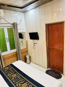 a room with a bed and a door and a tv at Hotel SK Residency in Varanasi
