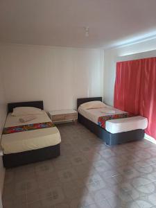 two beds in a room with red curtains at LG Palms in Sigatoka