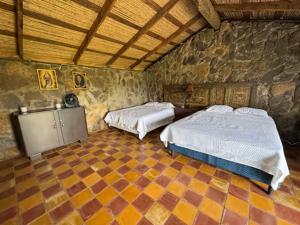 a bedroom with two beds and a stone wall at Casa Paz by Otium in La Cruz