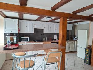 a kitchen with white cabinets and a counter with chairs at La Maison du Cordonnier in Fréland