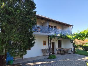 a house with a balcony and a table and chairs at Éva Apartmanház in Csopak