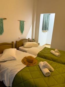 two beds in a room with towels and hats on them at Vasiliki Palli Rooms in Methana