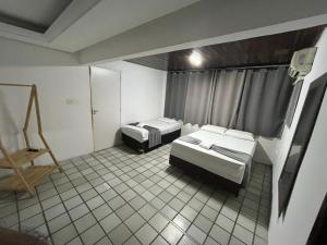 two beds in a room with a tiled floor at Pousada Trip Inn Recife in Recife
