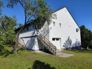a white house with a staircase on the side of it at Éva Apartmanház 2 in Csopak