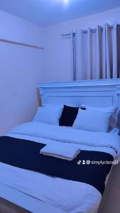 a bed with white sheets and pillows in a room at Banas Homes Kakamega in Kakamega