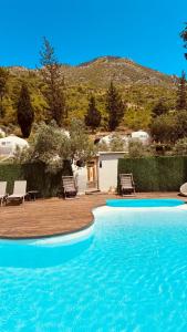 a large swimming pool with chairs and a house at Vita Nova Hotel in Olympos