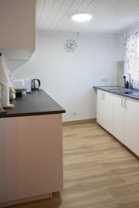 a kitchen with white cabinets and a black counter top at Casa con parra de uva y paz in Grou