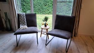 two chairs and a table in a room with a window at Vrijstaande bungalow met grote privé tuin dichtbij Veerse meer in Kortgene +49 photos