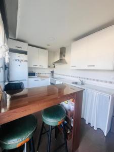 a kitchen with a counter with two green bar stools at Ático La Puerta de Logroño, con terraza y piscina! in Logroño