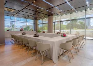 a long white table and chairs in a room with windows at Estelar Alto Prado in Barranquilla +35 photos
