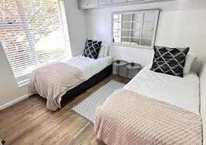 a bedroom with two beds and a window at The Fairway Apartment in Plettenberg Bay +41 photos