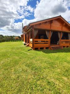 a wooden cabin in a field with a grass field at domek przy Jodłowej in Niesulice