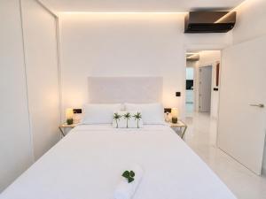 a bedroom with a white bed with two plants on it at Holibai Antia Mare Centro de Baiona y mar in Baiona