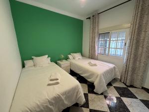 two beds in a room with a green wall at La Casuca del Chiguito in Chipiona