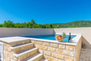 a stone retaining wall with stairs next to a swimming pool at House Romance for two in Zagvozd