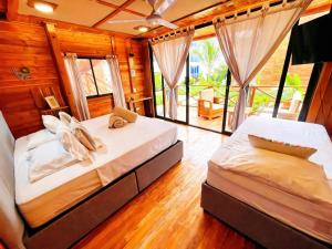 two beds in a room with wooden walls and windows at Eco hotel oasis del mar in Cartagena de Indias