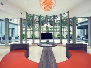 a room with a tv and a table andwindows at Mercure Hotel Brussels Centre Midi in Brussels