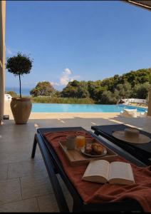 a table with a plate of food and a book at Galinio Boutique Apartments in Skafidia