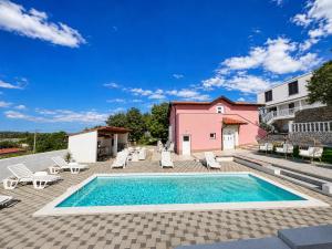 a swimming pool with lounge chairs and a pink building at Vila Neyra in Pula