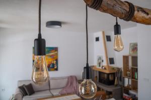 a living room with four lights hanging from a beam at Kaba Home - Mountain Villa with Sauna in Stoykite