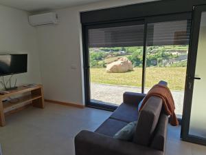 a living room with a couch and a large window at CabrilHome - AL Gerês in Cabril