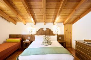 a bedroom with a bed and a wooden ceiling at Hotel Beau Sejour in Etroubles