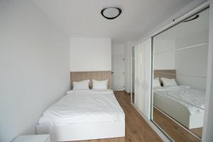 a white bedroom with two beds and a window at Izium Central Residence in Baia Mare