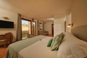 a bedroom with a bed with a desk and a television at Hotel Rural Es Riquers in Porreres +41 photos