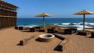a beach with umbrellas and chairs and the ocean at La Ballenera Lodge in Guaquen +4 photos