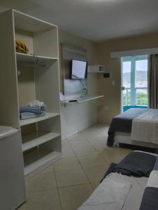 a room with a bedroom with a bed and a television at Pousada Mirante da Prainha in Arraial do Cabo