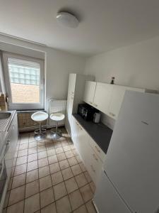 a kitchen with white cabinets and two stools in it at Ans soleil in Ans