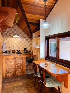 a kitchen with a wooden table and a dining room at Chalé Coração de Monte Verde in Monte Verde