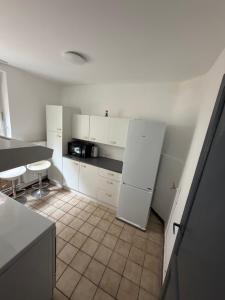 a kitchen with white cabinets and a white refrigerator at Ans soleil in Ans +2 photos