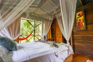 a bedroom with a bed with curtains and a window at Pure Roots in Bastimentos