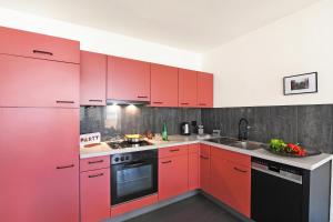 a kitchen with red cabinets and a sink at Malibu46 - Minusio Apt with Shared Pool & Balcony - Happy Rentals in Minusio +16 photos