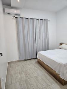 a bedroom with a bed and a window with curtains at Villa Princess Goofy in Lomé