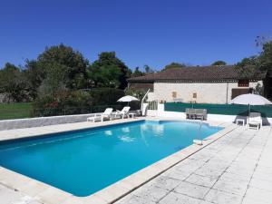 a large swimming pool with chairs and umbrellas at Gite du Fourbas in Belmont-Sainte-Foi