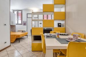 a dining room with yellow cabinets and a table and chairs at Alessia House in Ferrara