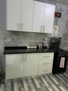 a kitchen with white cabinets and a black stove at Nana Kay's apartment in Livingstone