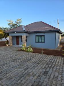 a small white house with a brick driveway at Nana Kay's apartment in Livingstone +4 photos
