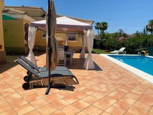 a chair and an umbrella next to a swimming pool at Suite Huelva garden in Aljaraque
