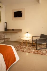a bedroom with a bed and a table and a tv at Los Lirios Hotel Merida in Mérida