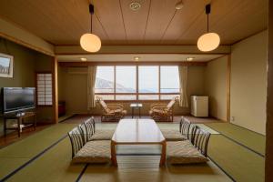 a room with a table and chairs and a television at Nishihoppo Onsen HOTEL in Yamanouchi