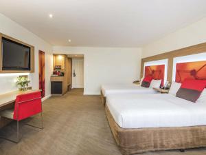 a hotel room with two beds and a flat screen tv at Novotel Sydney West HQ in Rooty Hill