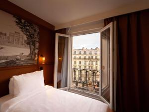 a bedroom with a window with a view of a building at Mercure Paris Bastille Marais in Paris
