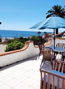 a patio with a table and an umbrella and the ocean at Ocean view house - Plaza del Mar in Rosarito