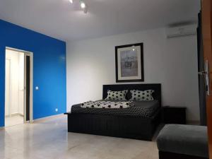 a bedroom with a black bed with a blue wall at RESIDENCE ADSL Studio BOUYGUES in Dakar