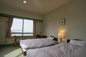 a hotel room with two beds and a window at Nishihoppo Onsen HOTEL in Yamanouchi