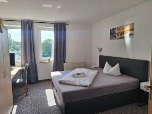 a bedroom with a bed and a desk and a window at Hotel am Zellwald in Großschirma +19 photos